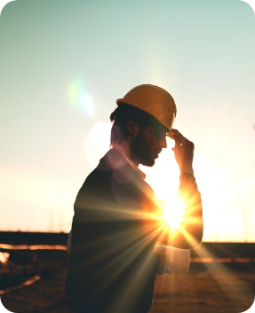 man in hardhat backlit with sun shining behind him