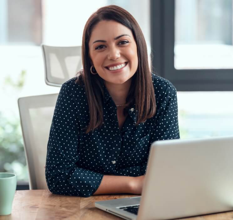 Aquila - woman smiling at camera over an open laptop